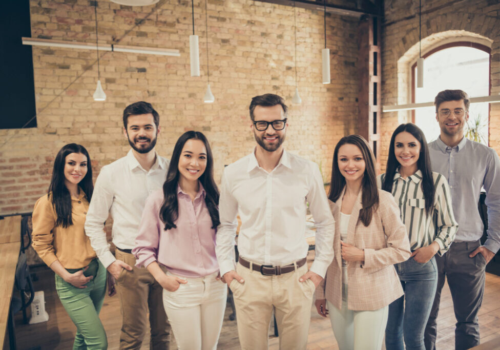 Photo of handsome business man pretty lady people partners stand, spacious big office seven members best friends successful teammates professionals good mood relationship indoors